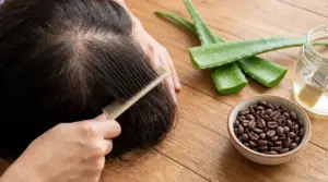 Persona che pettina i capelli con diradamento visibile sul cuoio capelluto, accanto ad aloe vera e caffè